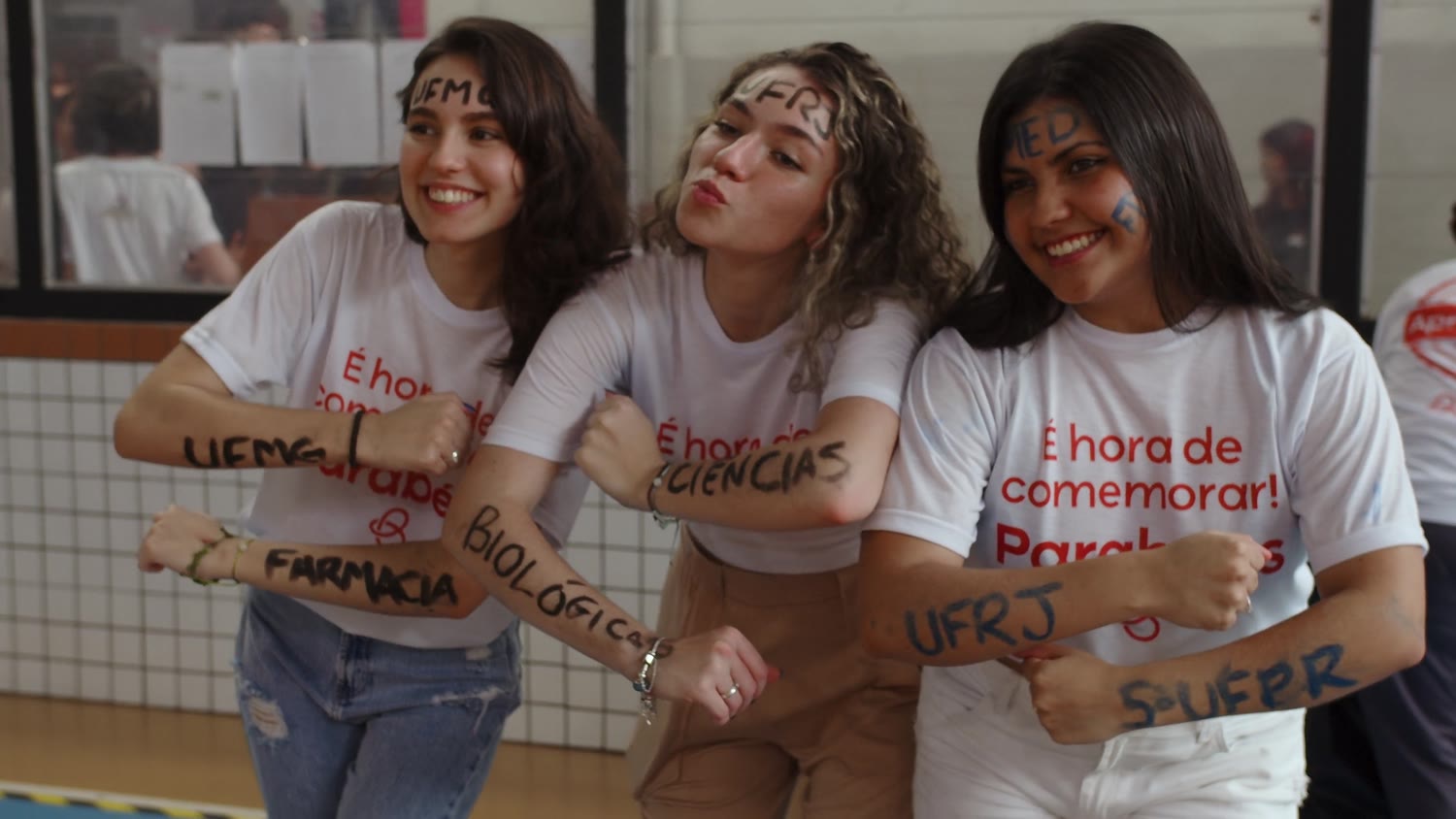 Três alunas aprovadas, com os cursos escritos nos braços