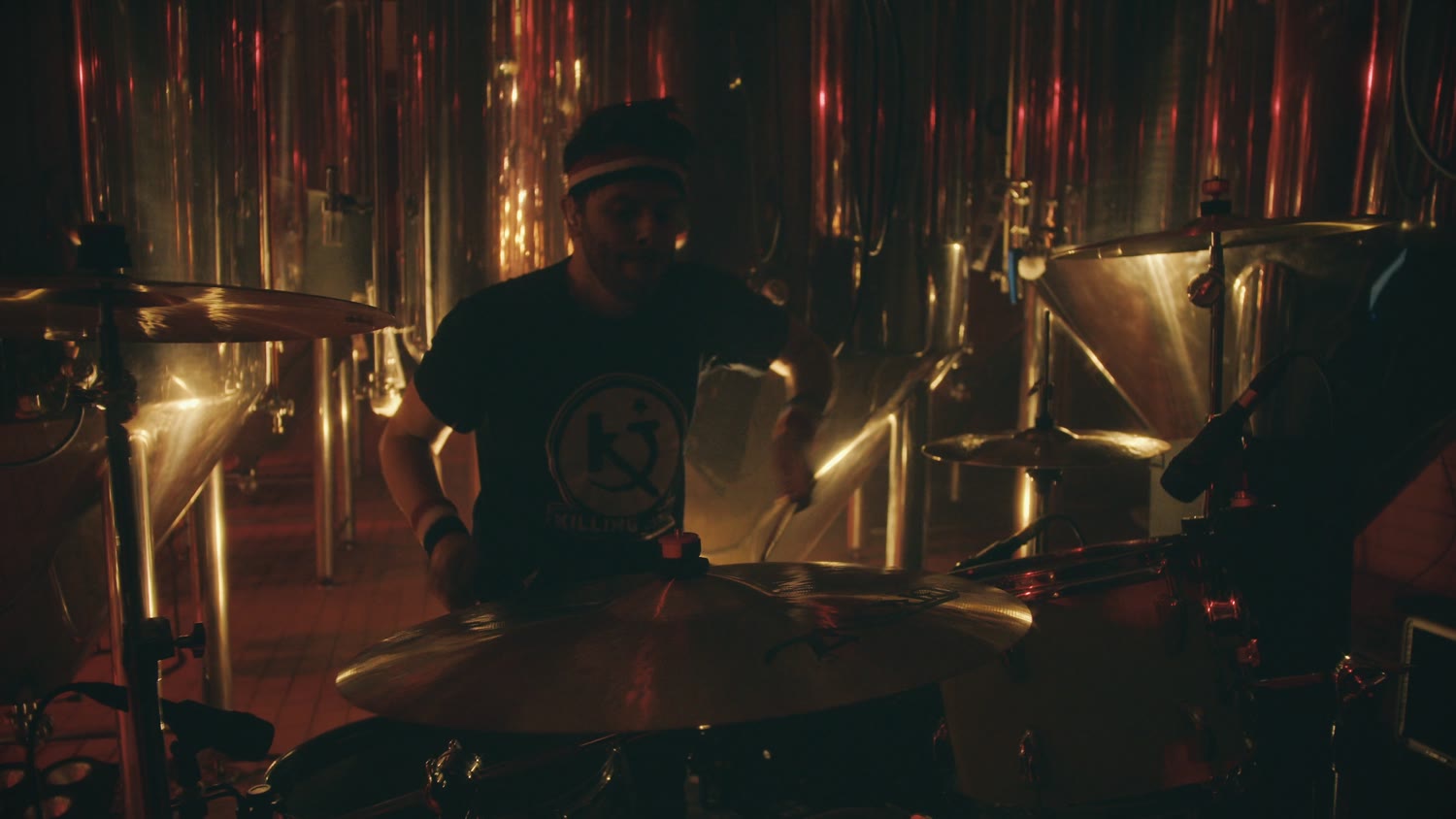 O baterista no meio dos tanques de cobre da cervejaria