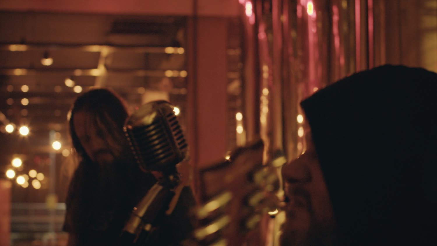 O vocalista no microfone, com a cervejaria desfocada atrás